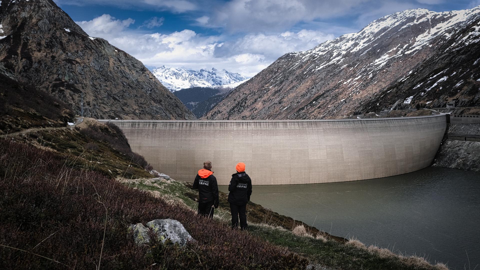 Surveyors looking at hydropower dam in the Swiss Alps during a sub-millimeter-resolution UAS dam survey by Orthodrone 
